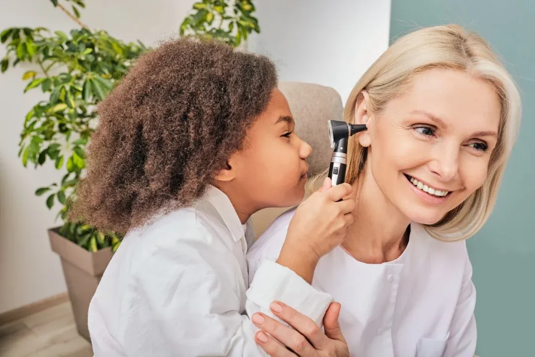 A clinician treating a child&rsquo;s ears in a playful way